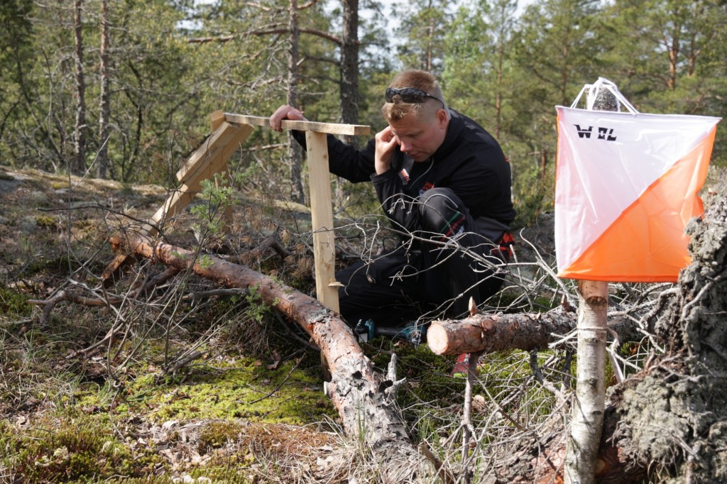 Jukolakavlens banläggare Jukka Oksa lägger kontrollutrustning på plats. Foto: Jari Virtanen.